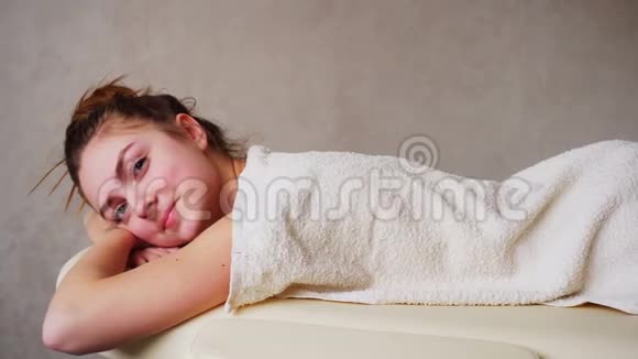 女孩在整容后放松看着相机躺在明亮的医疗办公室的沙发上视频的预览图