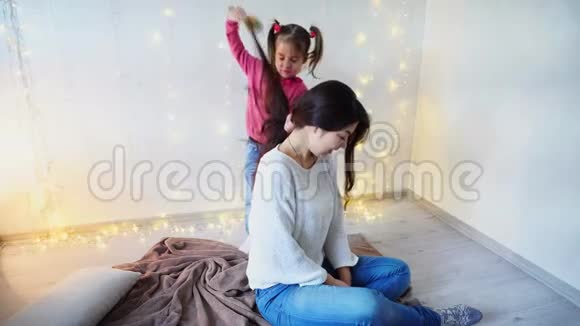 年轻的孩子照顾妈妈在家里做发型在的背景上的发型视频的预览图