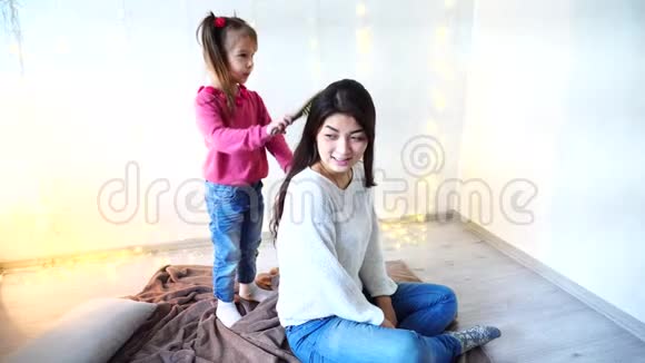 年轻的孩子照顾妈妈在家里做发型在的背景上的发型视频的预览图