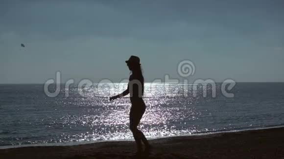 年轻女子在海滩上跳海背景的剪影慢动作视频的预览图
