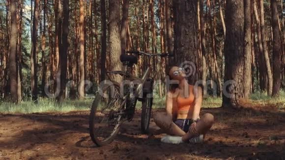 一位年轻的美女坐在树下骑着自行车视频的预览图