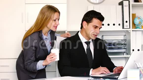 穿着黑色西装的微笑商人与办公室的女同事交谈视频的预览图