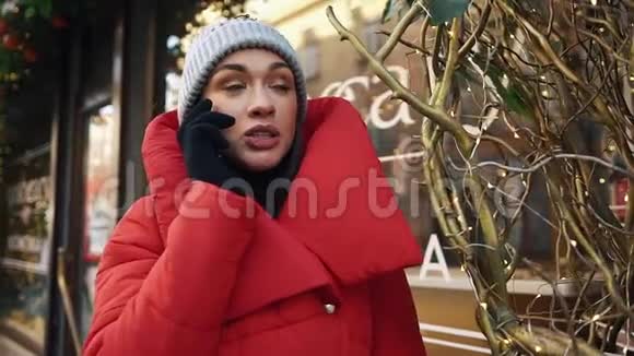 站在寒冷的冬天的街道上一个迷人的女人在电话里交谈时看上去很开心视频的预览图