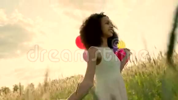 日落时分年轻女孩带着彩色气球穿过麦田视频的预览图