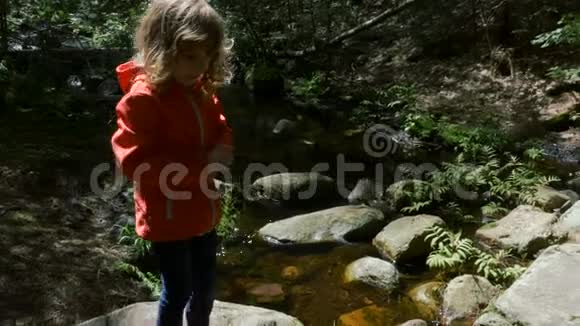 在森林中水晶清澈的溪流前的孩子视频的预览图