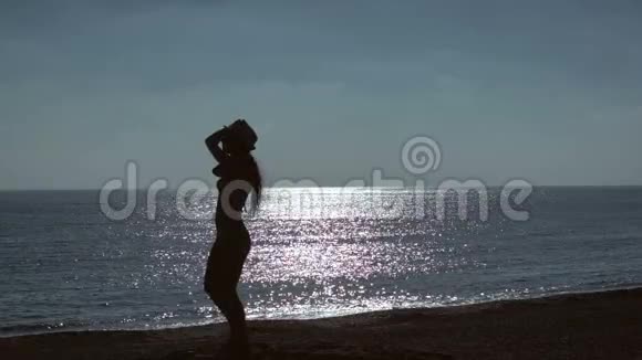 年轻女子在海滩上跳海背景的剪影慢动作视频的预览图