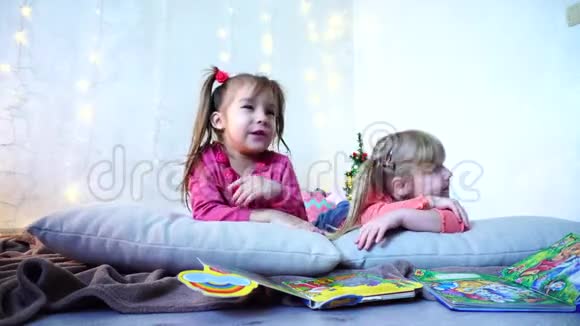 可爱的小女孩一起玩耍聊天躺在地板上枕头靠墙戴着花环和圣诞树视频的预览图