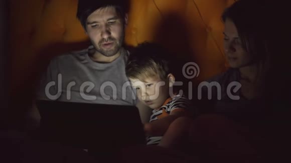 幸福的家庭和小儿子学习玩平板电脑躺在家里晚上视频的预览图