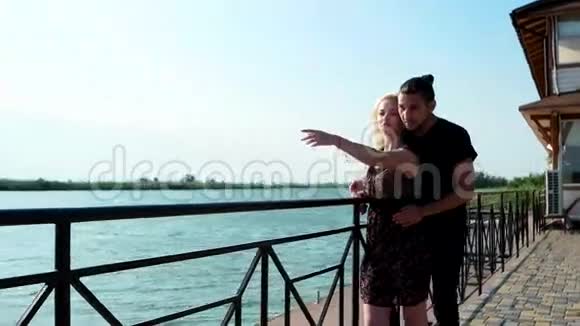 美丽的情侣站在石质码头上年轻的情侣站在风景的背景下视频的预览图