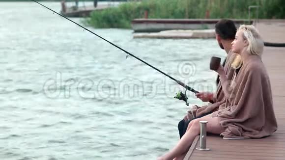 情侣们坐在码头上一起钓鱼一起喝热茶视频的预览图