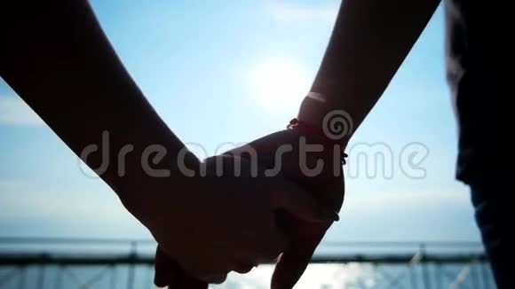 年轻的情侣牵着彼此的手在海岸漫步浪漫的情侣在阳光下爱在空中视频的预览图