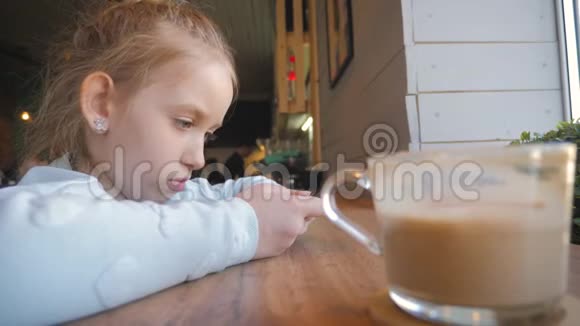 可爱的小女孩在咖啡馆里用智能手机快乐的孩子在放学后玩得开心和放松自然室内视频的预览图