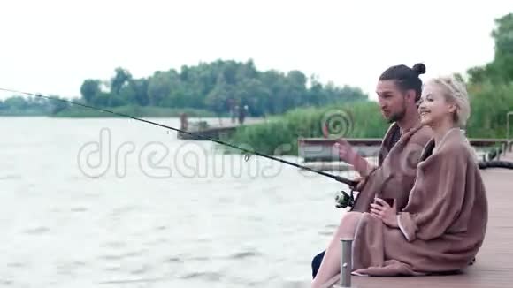 他展示了他可爱的女孩美丽的风景可爱的夫妇在码头上钓鱼喝杯咖啡视频的预览图