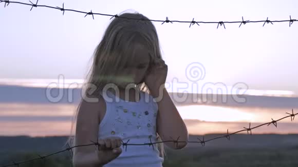 小女孩在铁丝网后面日落自由和移民的概念视频的预览图