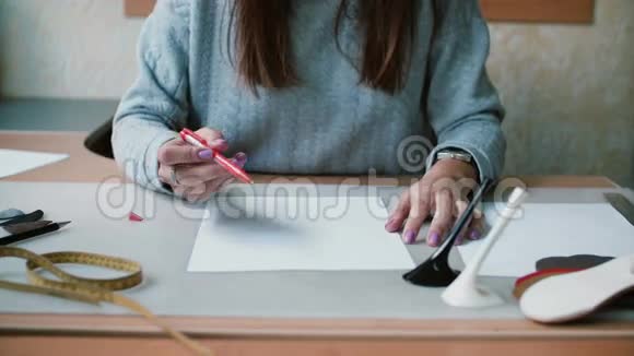 年轻女子坐在桌边拿着笔在白纸上准备画素描特写镜头4K视频的预览图