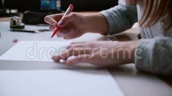 女人坐在桌子旁拿着铅笔在纸上画出布局在素描中擦除左转侧视4K视频的预览图
