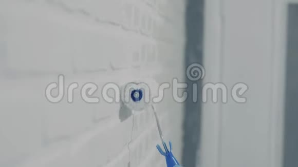 用灰色油漆的油漆滚筒把裸露的墙涂出来手绘使用油漆滚筒工作中的妇女视频的预览图