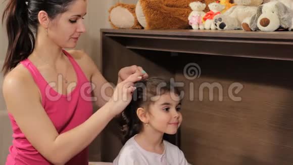 妈妈从美丽的卷发女孩的头上取下一个皱褶为梦想做准备视频的预览图
