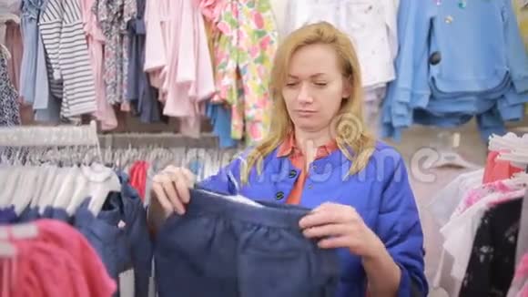 在一家儿童服装店购物的妇女儿童衣架上的衣服视频的预览图