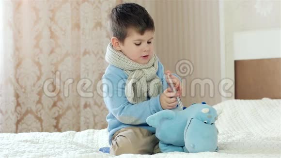 孩子生病了小男孩在玩医生治玩具在游戏中做刺注射脖子上戴围巾的孩子视频的预览图