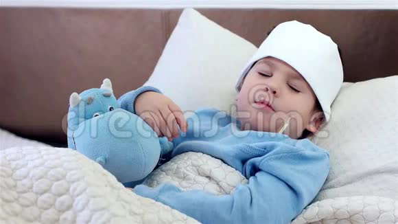生病的孩子睡觉孩子拿着电子体温计躺在床上生病时体温很高看上去很恶心很痛视频的预览图