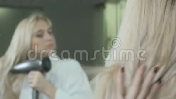 年轻女子用吹风机在镜子前擦干湿发视频的预览图