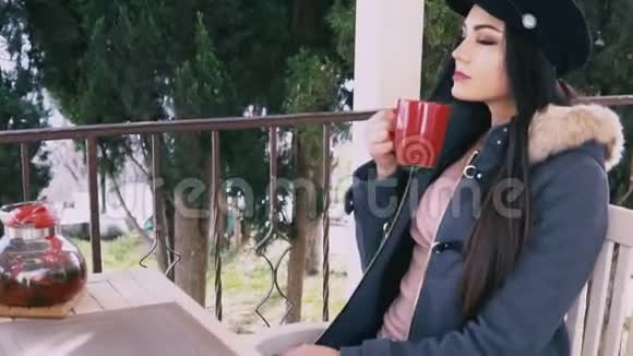 漂亮的黑发女人在街头餐馆喝热茶视频的预览图