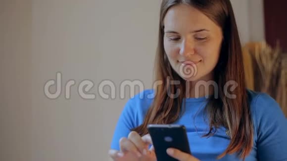 孕妇坐在家里客厅的沙发上用手机发短信视频的预览图