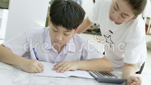 亚洲母亲的慢动作帮助她的儿子在白色桌子上做作业视频的预览图