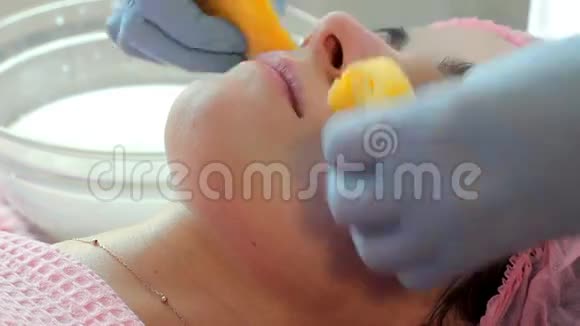 女人被用亮黄色的海绵从面罩上洗掉完善程序视频的预览图