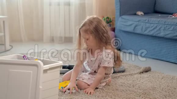 一个女孩在家里坐在地板上的盒子里收集玩具视频的预览图