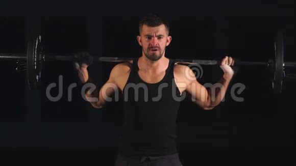专业健身者锻炼与杠铃在黑色背景肌肉男训练蹲头上有杠铃视频的预览图