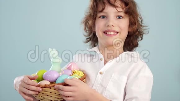 一个孩子拿着一只复活节兔子和一套装饰的复活节彩蛋男孩高兴地笑了慢动作视频的预览图