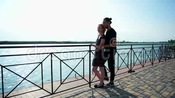 情侣们站在湖边的石码头上浪漫的年轻情侣们在一起视频的预览图