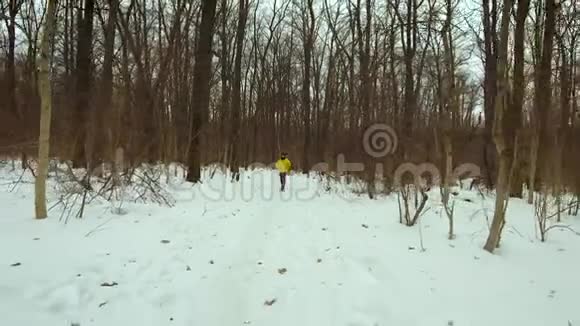 穿着黄色外套的小胡子在寒冷的冬日在森林里奔跑视频的预览图
