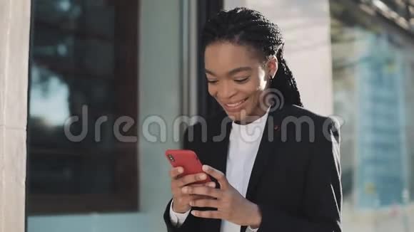 时尚的非洲女商人使用智能手机站在商业中心附近的街道上黑色时尚恐惧症视频的预览图