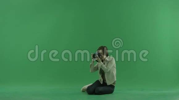 坐着的年轻女子正在绿色的屏幕上拍照视频的预览图