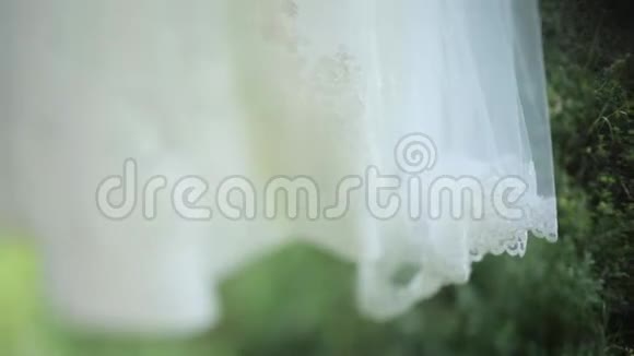 白色婚纱挂在花园的绿色秋千上视频的预览图