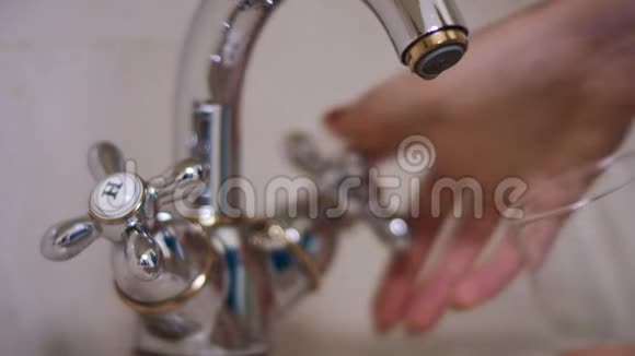 女人手把水从厨房的水龙头倒进玻璃视频的预览图