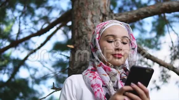 戴头巾的穆斯林在夏季公园用手机与朋友交流视频的预览图