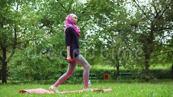 夏季公园里蹲着哑铃的穆斯林年轻女子视频的预览图