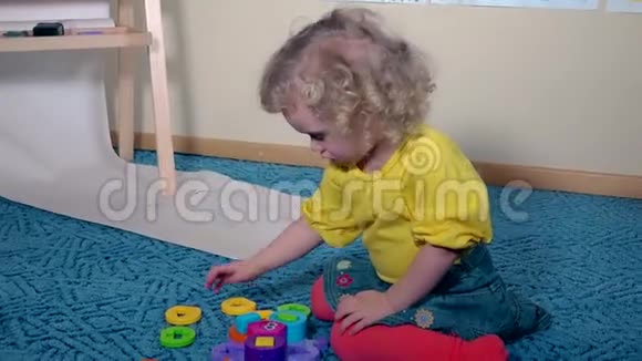 可爱的聪明女孩把塑料玩具小提琴放在地毯地板上视频的预览图