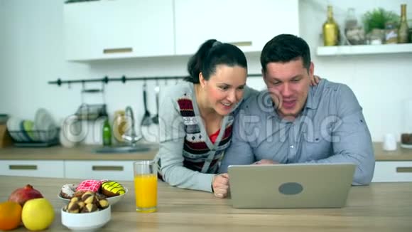 白人夫妇在厨房用电脑家庭技术和人际关系概念微笑的夫妻视频的预览图