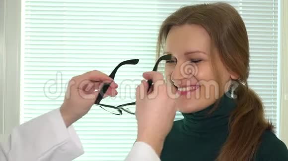 带着眼科医生对着明亮的窗户尝试新眼镜的女人视频的预览图
