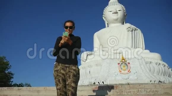 泰国普吉岛的年轻旅游女孩制作白色大佛像自拍照片高清视频的预览图
