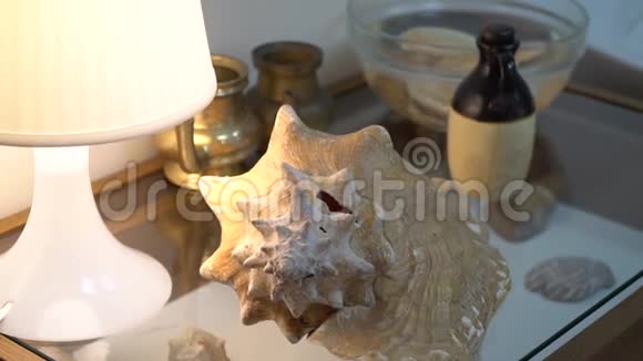 玻璃桌上带有芳香油的罐子前的装饰壳用于按摩视频的预览图