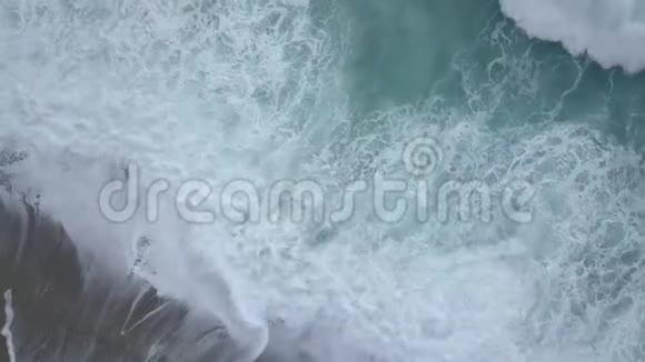 从高空俯瞰海浪的泡沫和飞溅打破了空荡荡的海滩视频的预览图