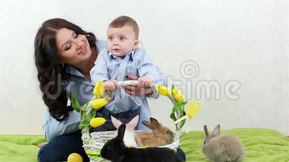 兔子在篮子里爬行年轻的母亲和她的儿子坐在一起复活节兔子靠近柳条篮子视频的预览图