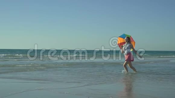 穿着带太阳镜的粉红色裙子的疯狂滑稽女人在海滩上奔跑和跳跃假期来了快乐女孩跳跃视频的预览图