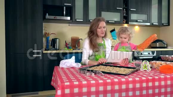 情绪化的母女在平板电脑上学习糖果食谱视频的预览图